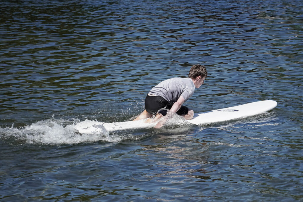 Ian paddles with his arms on a surfboard.